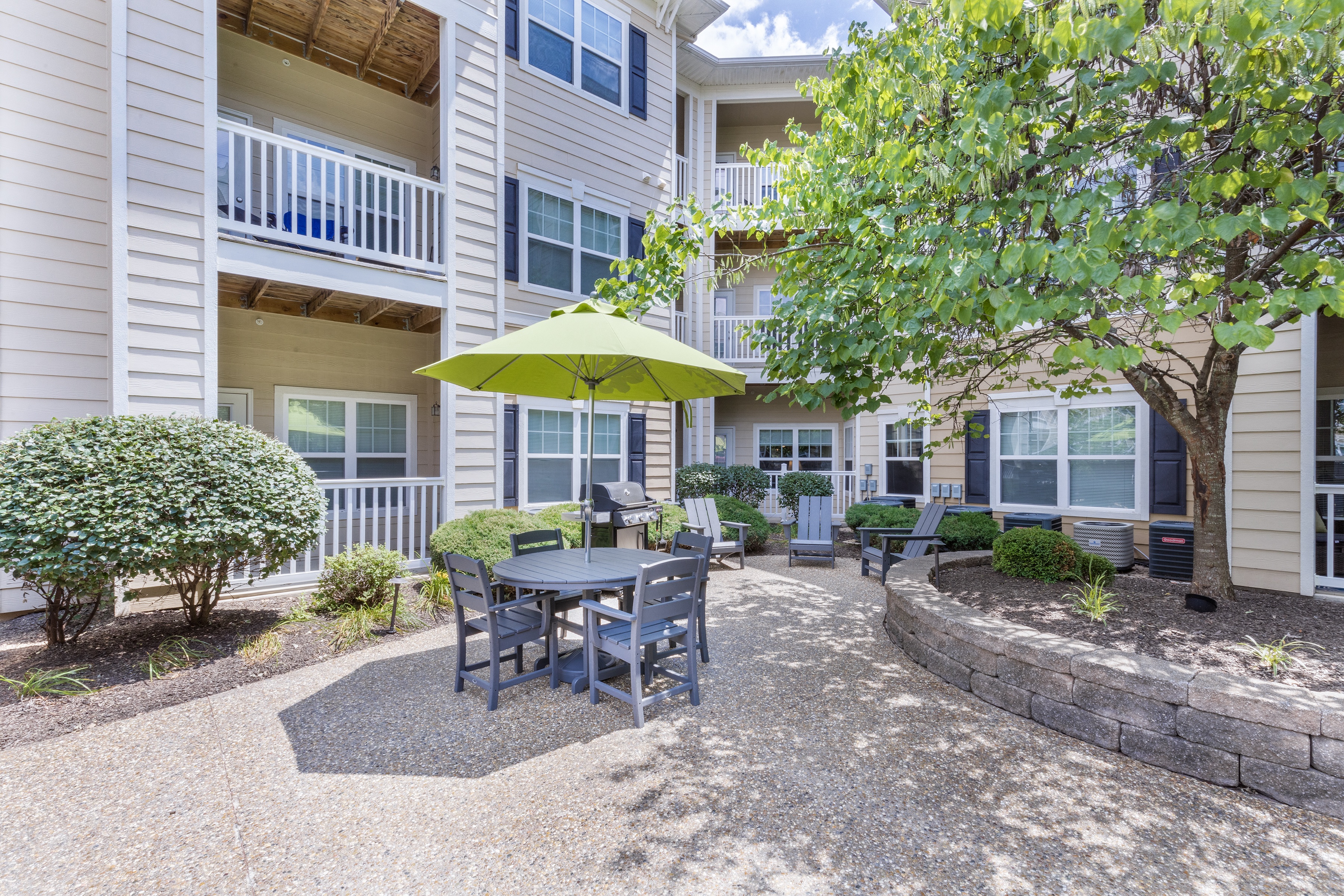 a patio with a table and chairs under an umbrella at Aventura at Forest Park, St. Louis